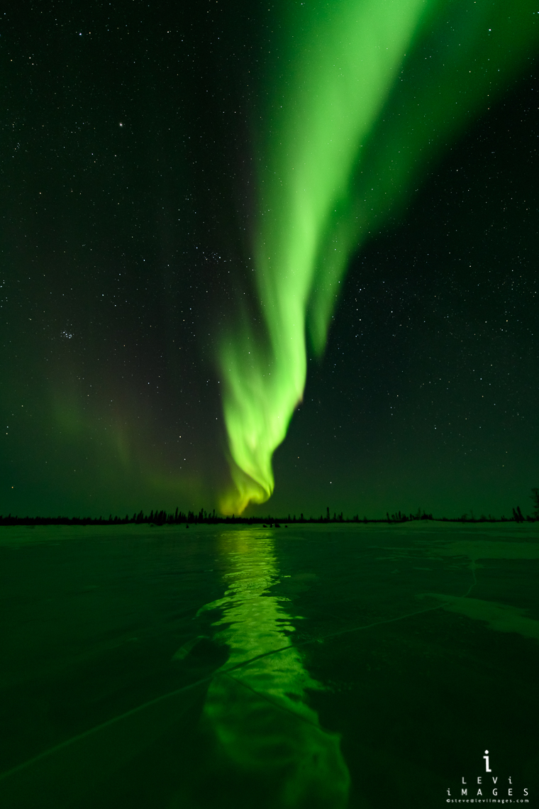 Northern lights reflected on lake ice. Manitoba, Canada