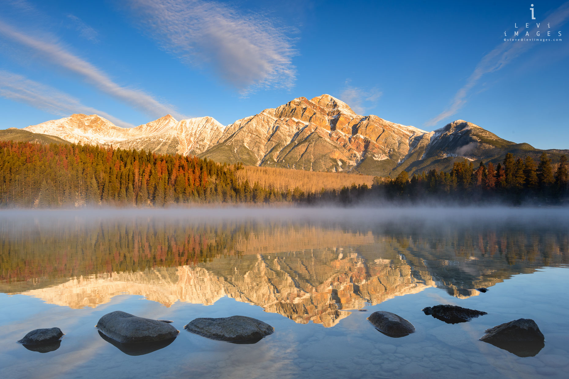 Mountains and autumn trees reflected in Lake Patricia at sunrise. Jasper, Alberta, Canada