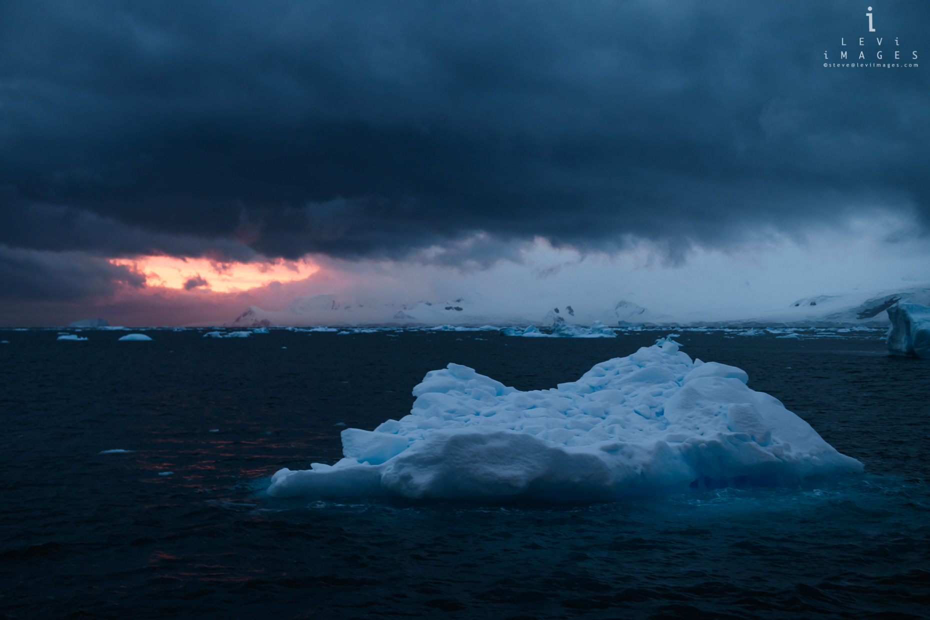 Dramatic sunset breaks through storm clouds over Antarctic landscape