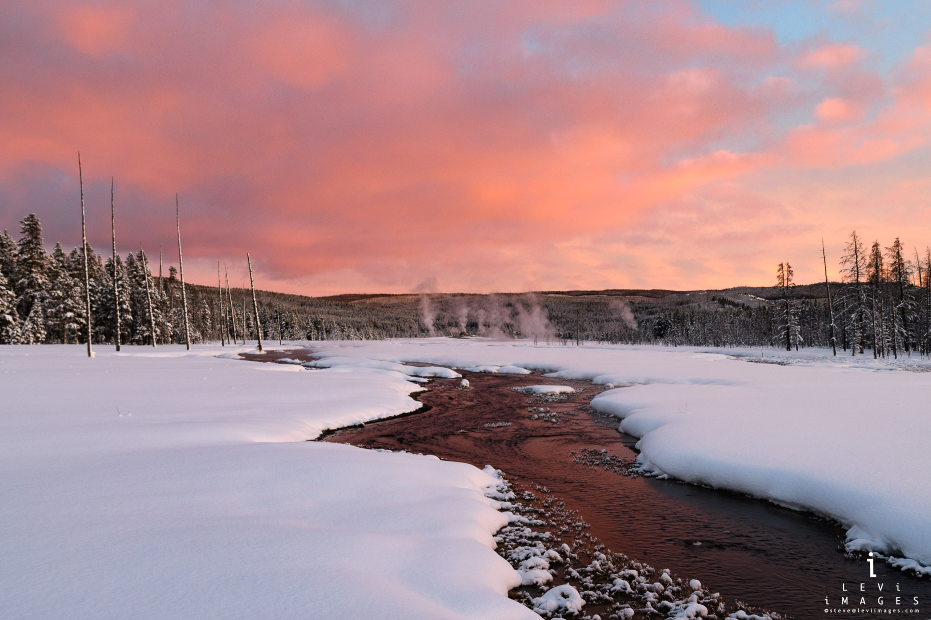 Sunset is reflected in stream with thermal features in the background. Yellowstone National Park, Wyoming